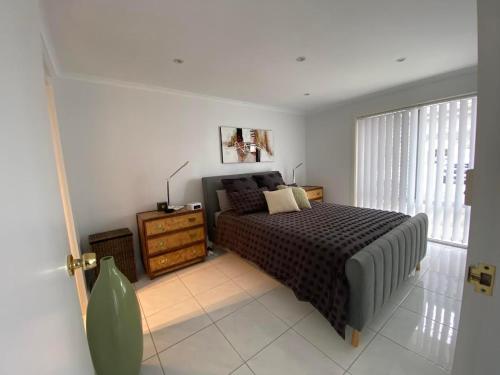 - une chambre avec un lit, une commode et une fenêtre dans l'établissement Port Lincoln Marina Waterfront Apartment, à Port Lincoln