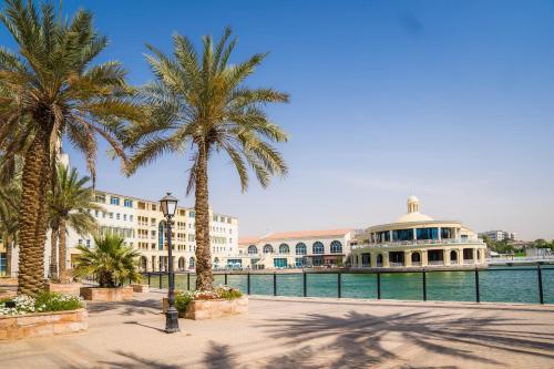 a group of palm trees and a building next to the water at Copthorne Lakeview Executive Apartments Dubai, Green Community in Dubai