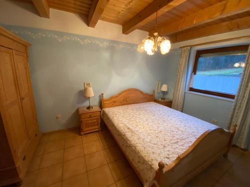 a bedroom with a bed and a window and a chandelier at Gartenwohnung im Gut Sonnenwald in Schöllnach