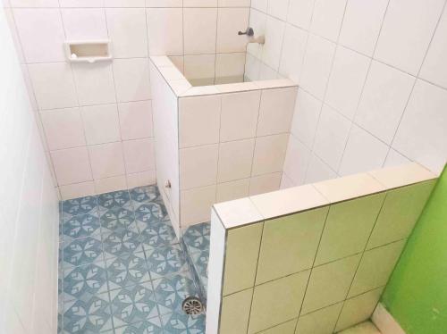 a small bathroom with a shower with a tiled floor at Bayu Murti Inn Kaliurang Yogyakarta RedPartner in Kaliurang