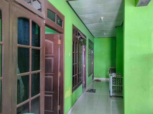 an empty hallway with green walls and wooden doors at Bayu Murti Inn Kaliurang Yogyakarta RedPartner in Kaliurang
