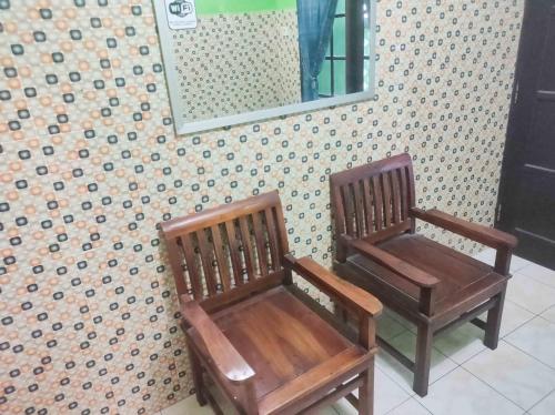 two wooden chairs sitting next to a wall with a mirror at Bayu Murti Inn Kaliurang Yogyakarta RedPartner in Kaliurang