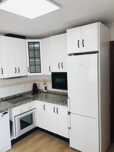 a kitchen with white cabinets and a white refrigerator at AT VISTA GRANADA in Monachil