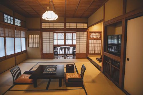 a dining room with a table and chairs and windows at Arima Onsen Tocen Goshobo in Kobe