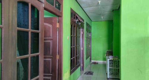 an empty hallway with green walls and wooden doors at Bayu Murti Inn Kaliurang Yogyakarta RedPartner in Kaliurang