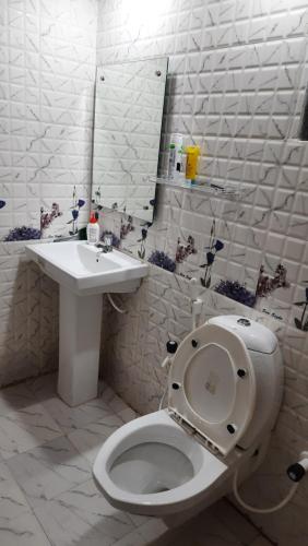 a white bathroom with a toilet and a sink at Nath's Residency in Puri