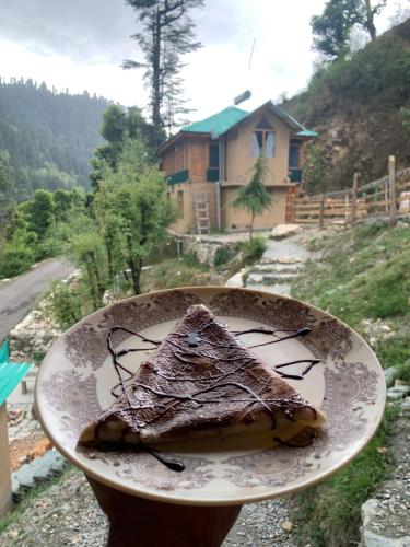 a plate with a piece of cake on top of a house at The Misty Wilds Home, Jibhi in Jibhi