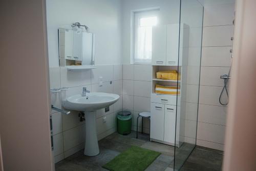 a white bathroom with a sink and a mirror at Gästehaus Jeindl in Hartmannsdorf