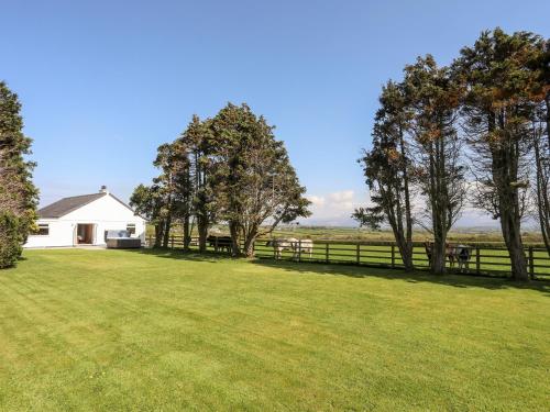 a large yard with a white house and trees at Mynydd Mwyn in Llanfairpwllgwyngyll