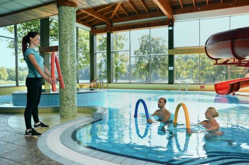 a woman and two children in a swimming pool at Sanatorija ,,Tulpės" in Birštonas