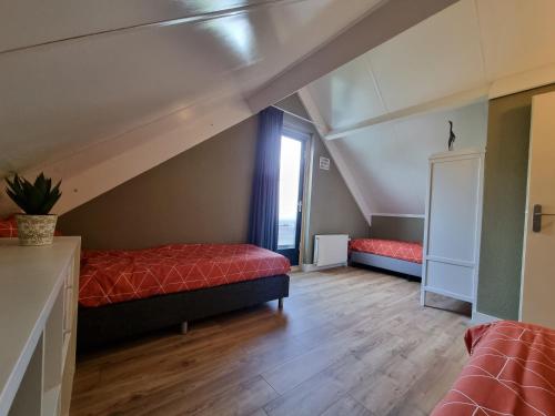 EwijkにあるFamily home, large garden, playground kids, firepit, terraces, sleeps max 7 and 1 babycot, kids playroom insideのベッド2台と窓が備わる屋根裏部屋です。