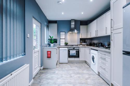 a large kitchen with white appliances and blue walls at Spacious Modern Chester Home - Great Location in Chester