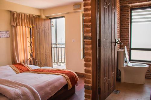 a bedroom with a bed and a bathroom with a window at HOTEL LAYAKU DURBAR in Bhaktapur