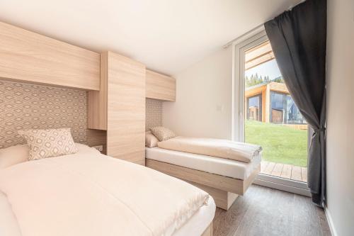 a bedroom with a bed and a large window at Chalets & Glamping Nassfeld by ALPS RESORTS in Kötschach