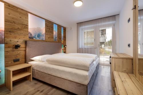 een slaapkamer met een groot bed en een houten muur bij Apartments Pragser Wildsee Winklwiese in Braies