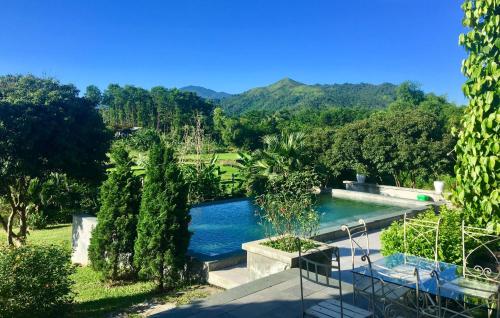 a swimming pool in a garden with mountains in the background at Yen Bai Garden Ba Vi - Venuestay in Hanoi