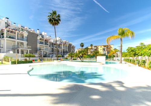 Una gran piscina con palmeras y condominios. en Sunny Denia Apartment 4U - Mar Baltic 5, en Denia