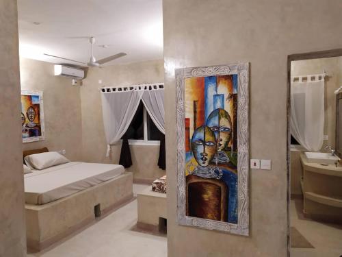 a bedroom with a bed and a painting on the wall at Garoda House Turtle Bay [ Jacuzzi ☆☆☆☆☆ ] Kilifi in Watamu