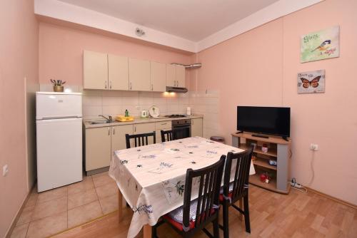 a kitchen with a table with chairs and a white refrigerator at Apartment Meri- near the Zadar main bus station in Zadar