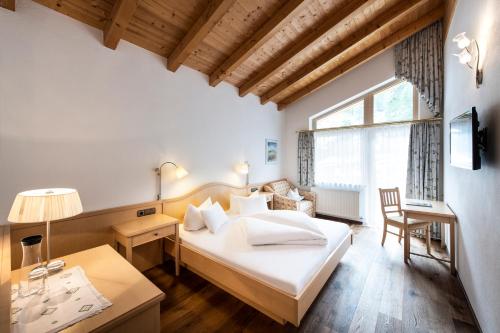 a bedroom with a bed and a desk and a window at Alpenland Gerlos - Hotel & Breakfast in Gerlos