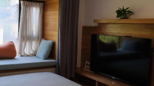 a bedroom with a tv and a bed and a window at Rock&Wood Cozy House in Hangzhou