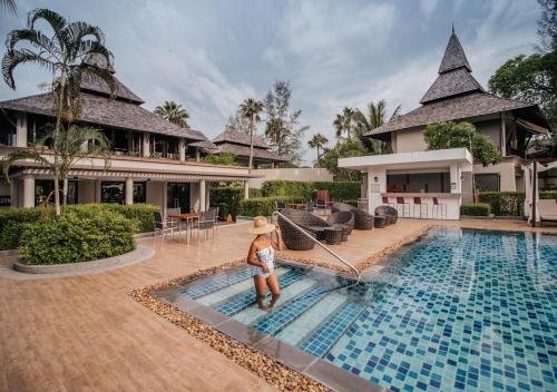 a child standing next to a swimming pool at a house at Layana Resort & Spa - SHA Extra Plus in Ko Lanta