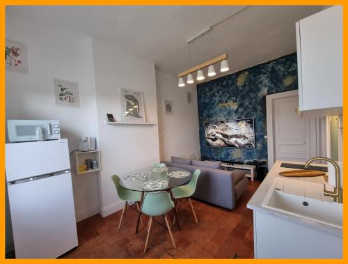 a kitchen and living room with a table and a couch at Gîtes du petit familistère Landrecies in Guise