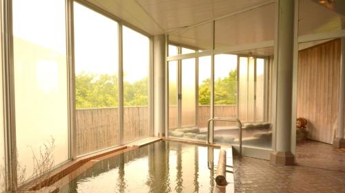an indoor pool in a house with windows at Tabist Hotel Colosseum Inn Tateshina in Tateshina