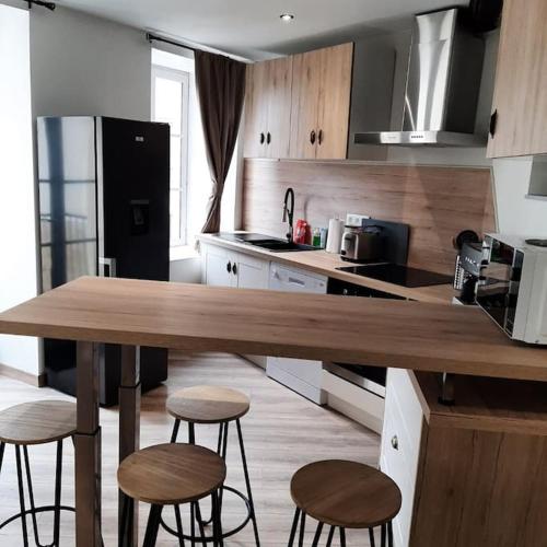 una cocina con mesa de madera y taburetes. en Maison de ville, en Vic-le-Comte