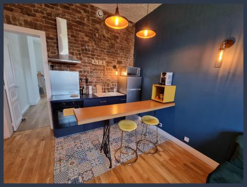 eine Küche mit einer Theke und Hockern in einem Zimmer in der Unterkunft Gîtes Familistère Landrecies - Guise in Guise