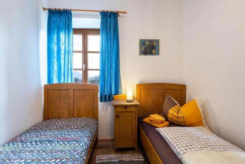 two beds in a room with blue curtains and a window at Sallrain Hof Apartment 1 in Collalbo
