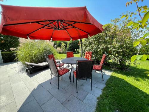 a table with chairs and a red umbrella at Ferienwohnung mit Terrasse und Garten in Seenähe in Bodman-Ludwigshafen
