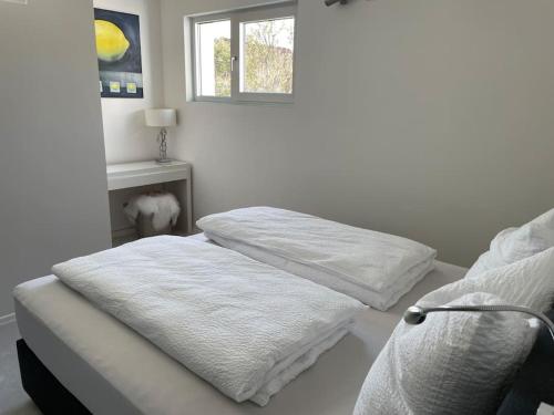 a bedroom with a bed with white sheets and a window at Ferienwohnung mit Terrasse und Garten in Seenähe in Bodman-Ludwigshafen