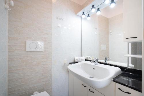 a white bathroom with a sink and a mirror at WePuglia - Dimora Capitolo in Monopoli