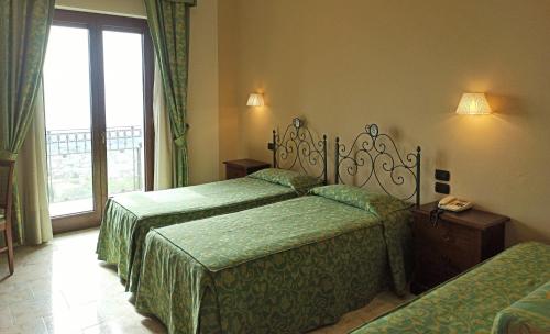 A bed or beds in a room at Hotel Primavera Dell'Etna