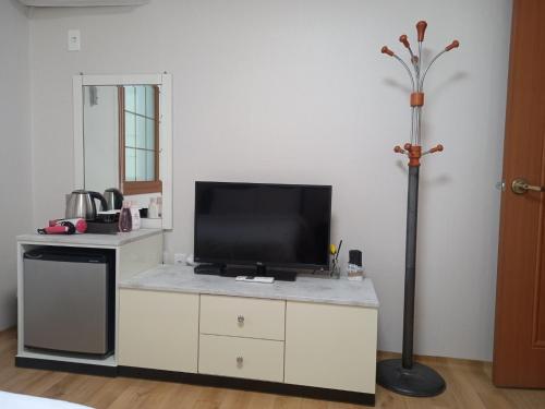 a living room with a tv on a white cabinet at Charlie Hotel Jeju in Jeju