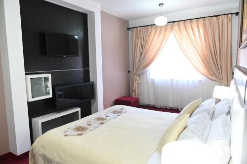 a bedroom with a bed and a tv on a wall at Hotel Liss in Lezhë