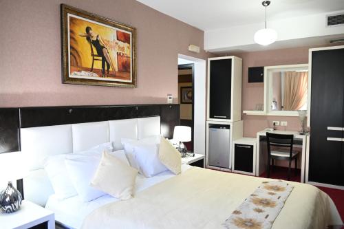 a bedroom with a white bed with a painting on the wall at Hotel Liss in Lezhë