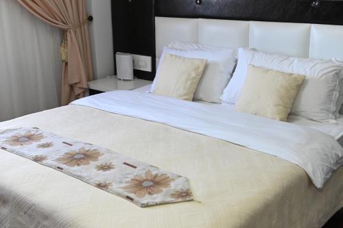a large white bed with a flower blanket on it at Hotel Liss in Lezhë