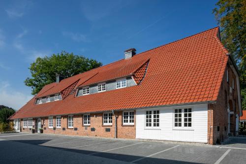 a brick building with an orange roof at Weberhof Ferienapartments in Rostrup am Westufer des Zwischenahner Meers in Bad Zwischenahn