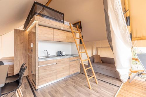 a tiny house with a kitchen and a ladder at Chalets & Glamping Nassfeld by ALPS RESORTS in Kötschach
