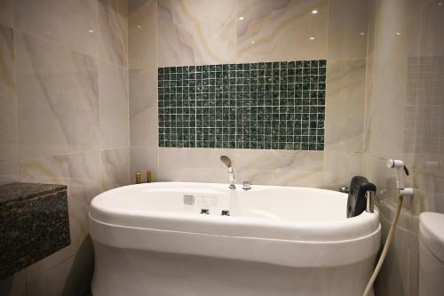a white tub in a bathroom with a green tile wall at Quiet Dreams - Serviced Apartments King abdul Aziz Street Branch in Jeddah