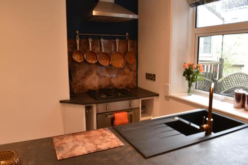 a kitchen with a stove with pots and pans on the wall at The Cheltenham, stylish 1-bed Victorian apartment in Harrogate