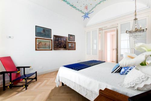 una camera bianca con un letto e una sedia rossa di AMORE RENTALS - Casa Sofia a Sorrento
