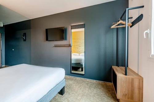グラディニャンにあるB&B HOTEL Bordeaux Talenceの白いベッドと鏡のある寝室