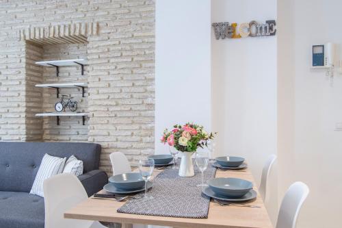 uma sala de jantar com uma mesa com cadeiras e uma parede de tijolos em Riverside Triana Apartment em Sevilha