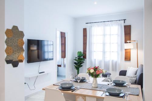 a white living room with a table and a tv at Riverside Triana Apartment in Seville