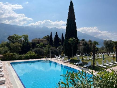 duży basen z krzesłami, drzewami i górami w obiekcie Village Bazzanega - Montagnoli Group w Tremosine Sul Garda