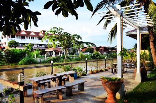 a row of wooden benches sitting next to a river at บ้านชมจันทร์ in Phra Nakhon Si Ayutthaya