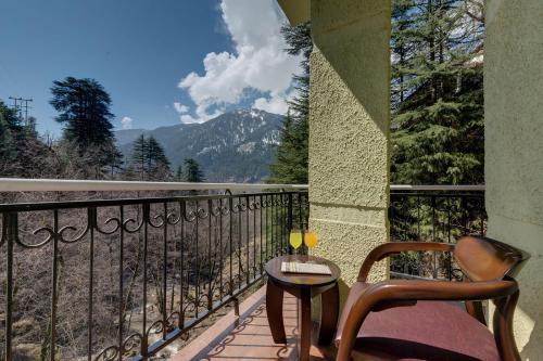a balcony with a table and chairs and a view of a mountain at Regenta Place Green Leaf Manali- A Centrally Heated Resort in Manāli